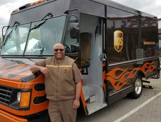man standing in front of UPS truck that has flames