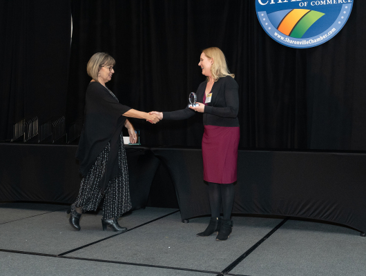 two women shaking hands while one holds award