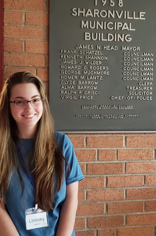 girl standing in front of Sharonville Municipal Building plaque